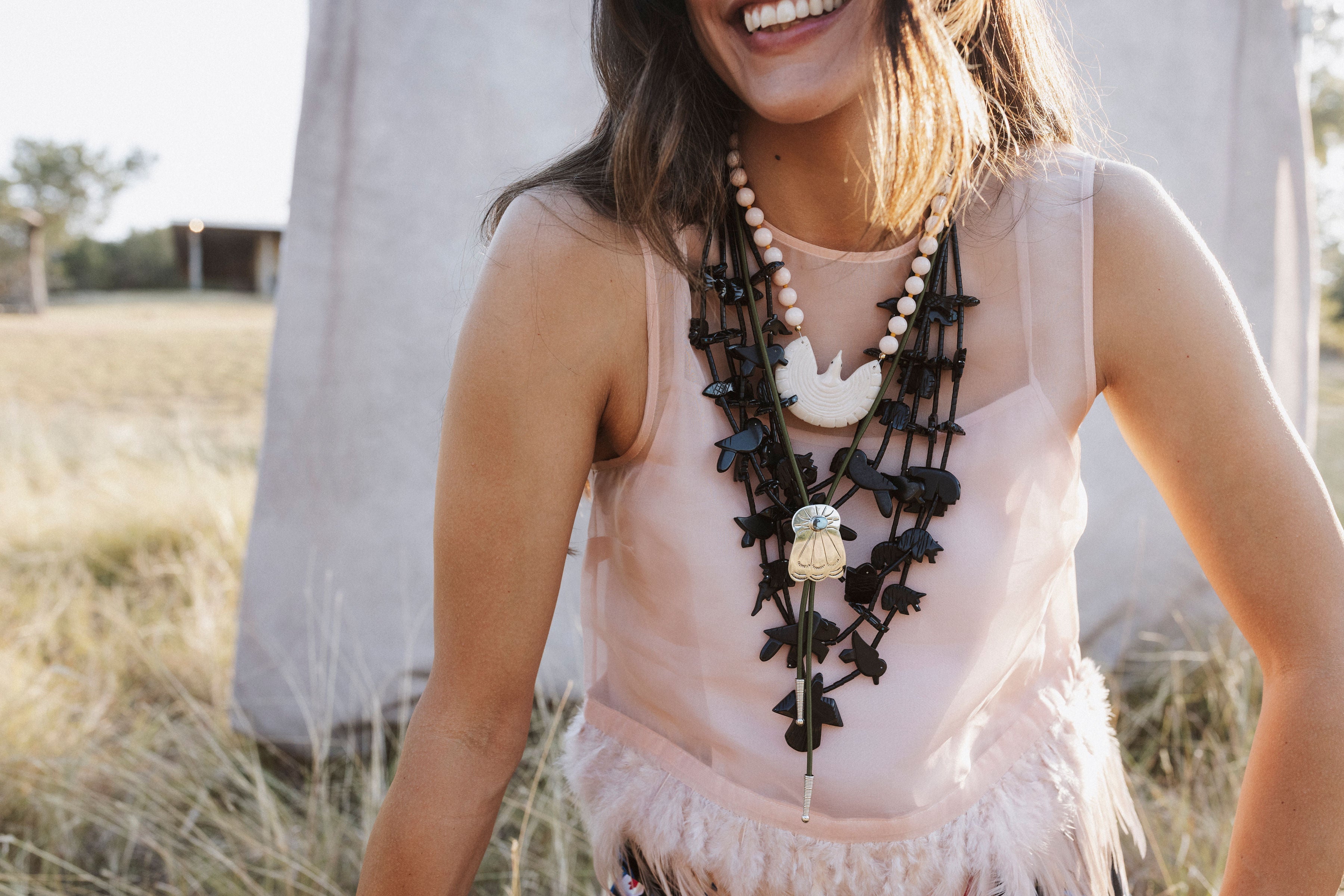 The Stack 05 layers worn together — Mother of Pearl Eagle, the black Multistrand Fetish, and a bolo on army green cord
